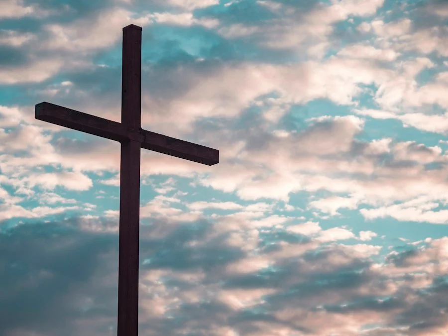 A church cross beneath a blue sky with soft clouds.