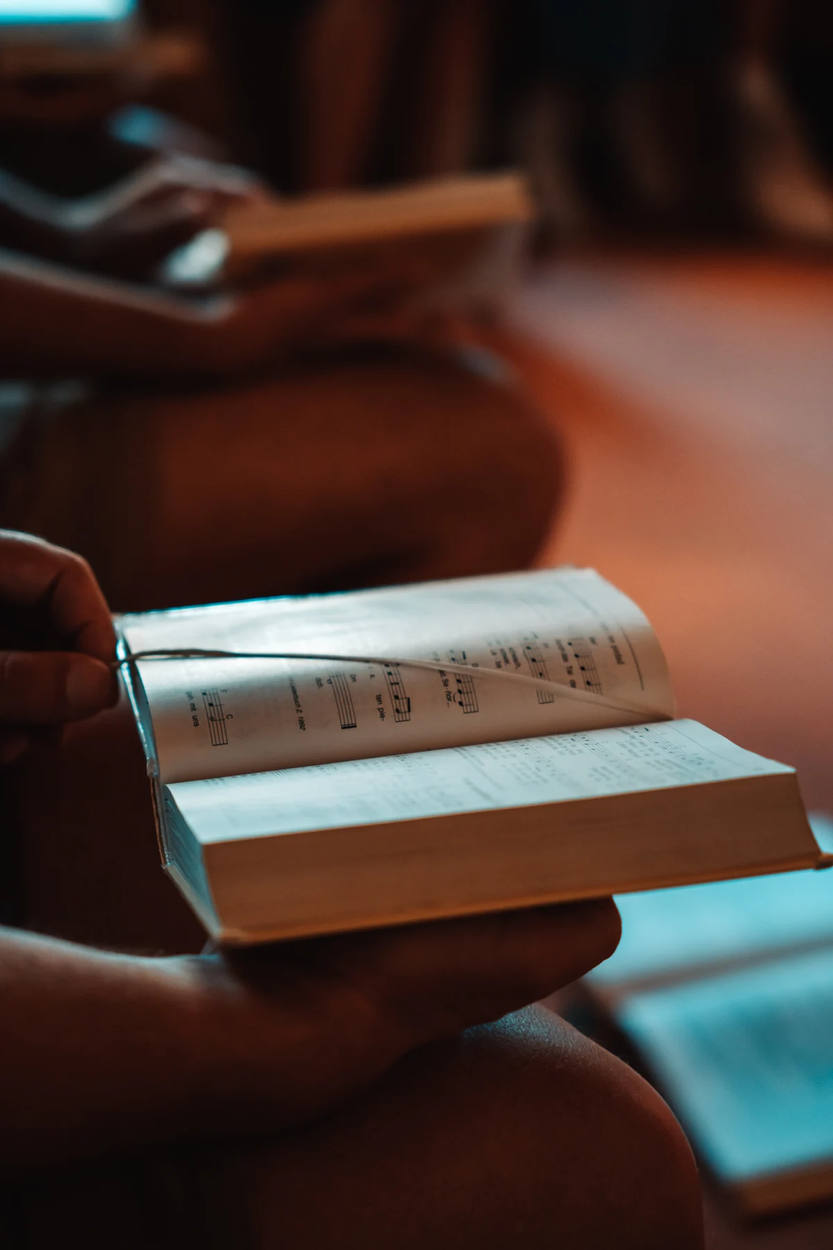 A worshipper holding an open hymn book with printed music.